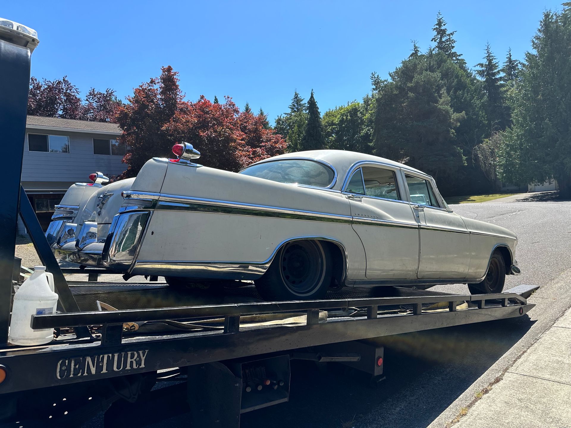 A white car is being towed by a century tow truck