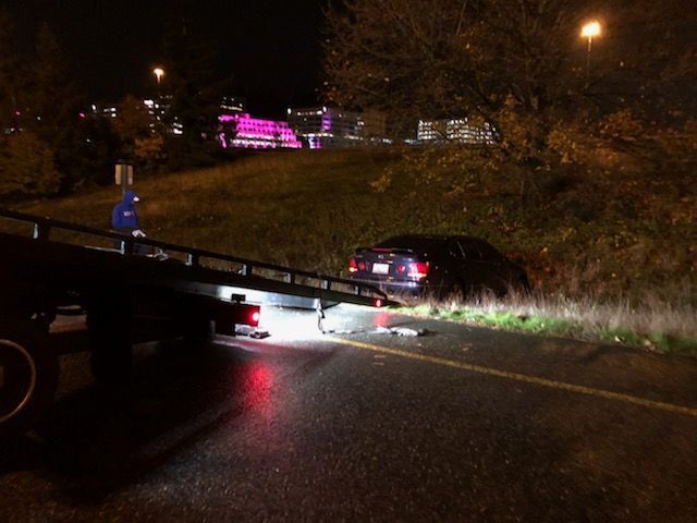 A car is being towed by a tow truck at night.