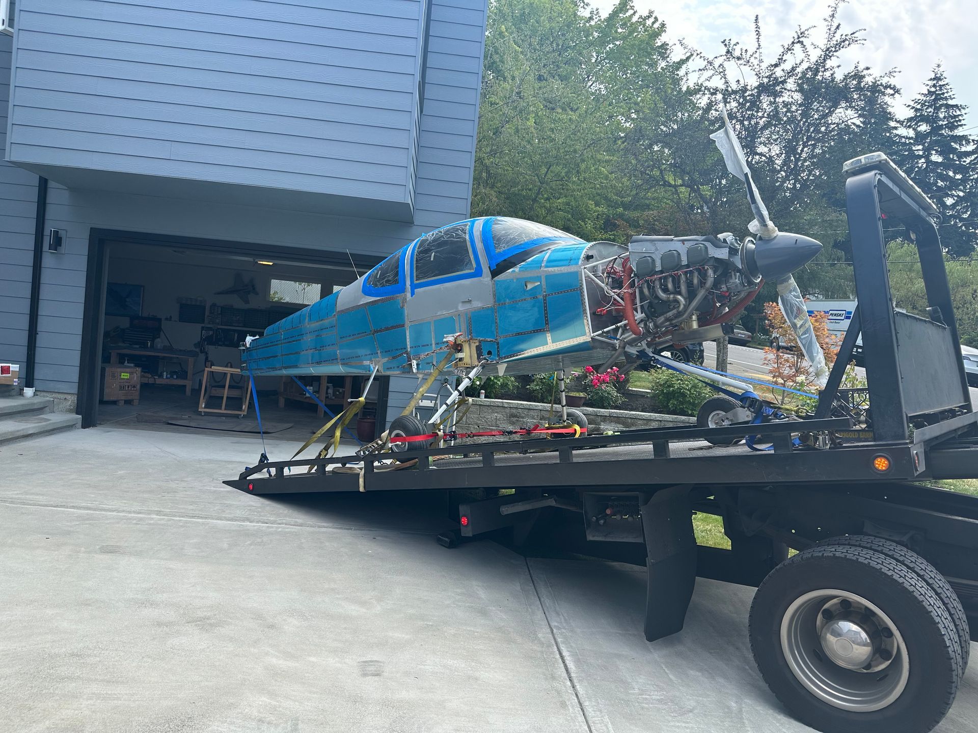 A small blue airplane is sitting on top of a tow truck.