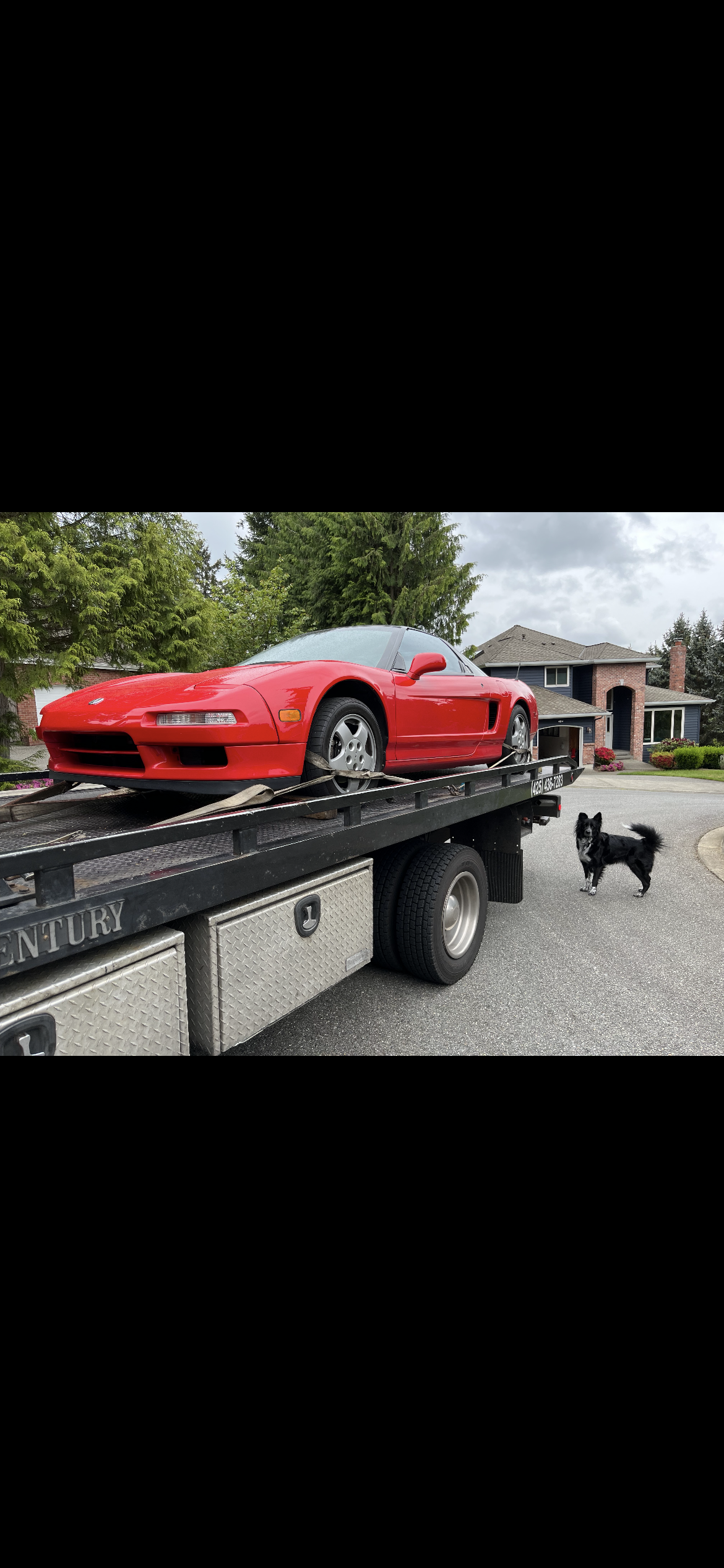 A red sports car is being towed by a tow truck.