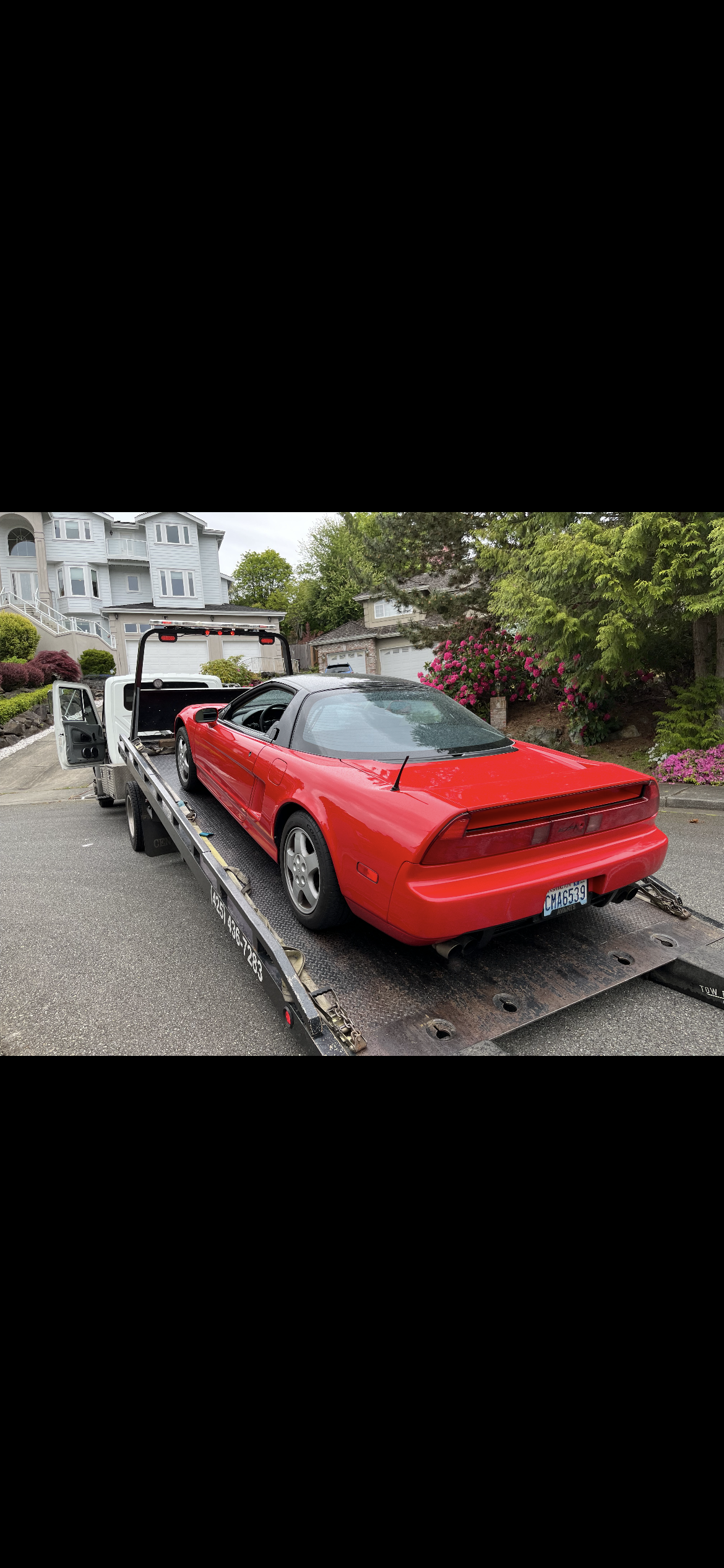 A red sports car is being towed by a tow truck.