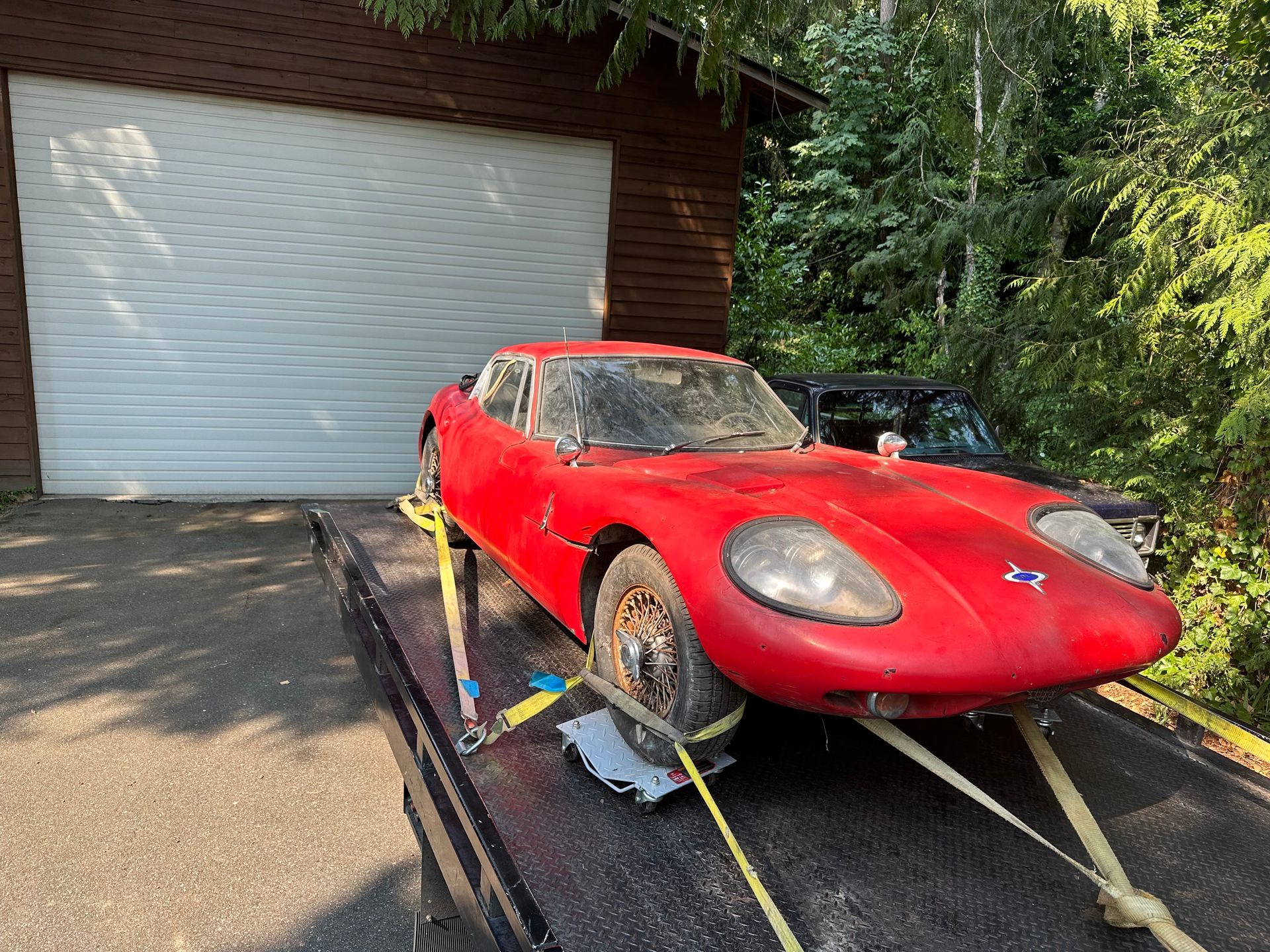 A red sports car is sitting on top of a tow truck.