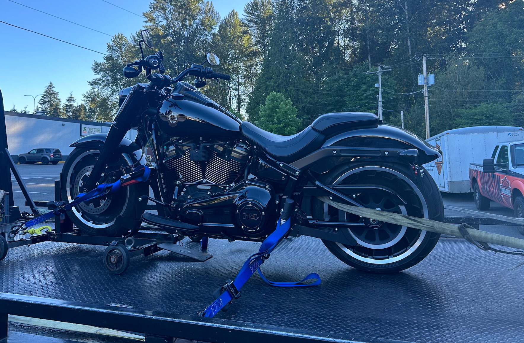 A black motorcycle is being towed by a trailer.
