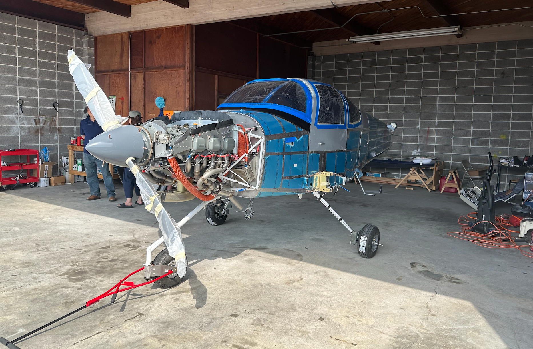 A small blue airplane is parked in a garage.