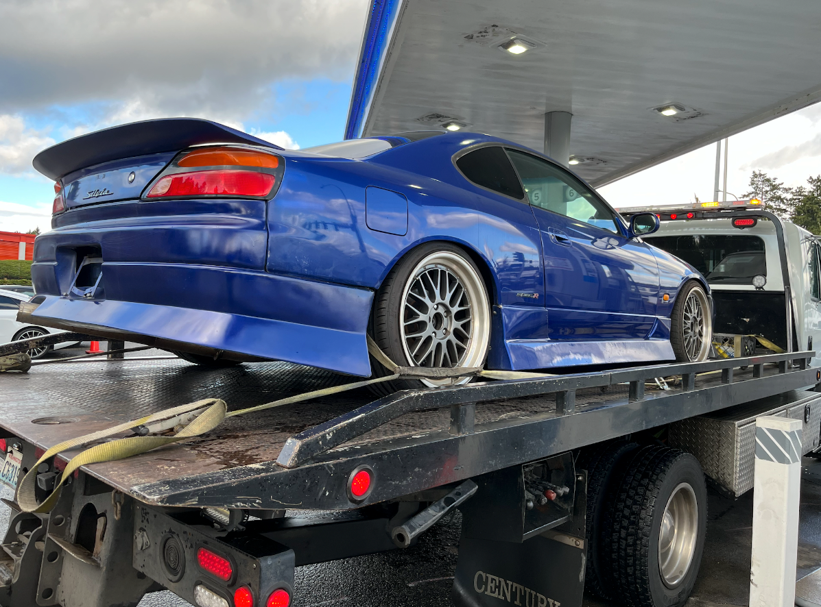 A blue car is sitting on top of a tow truck.