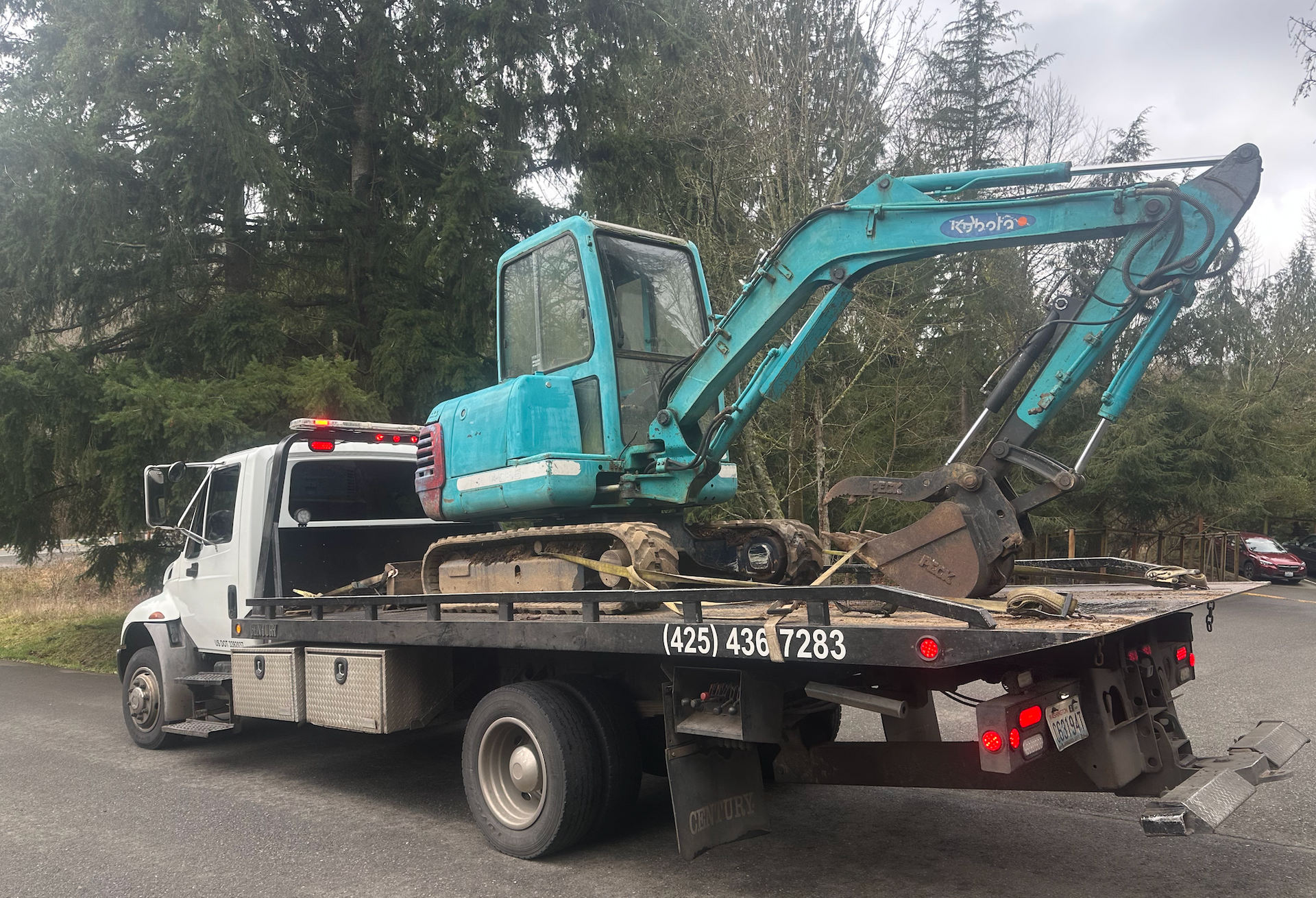 A tow truck with a blue excavator on the back of it