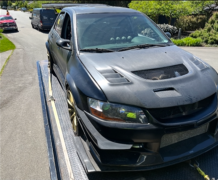 A black car is being towed by a tow truck