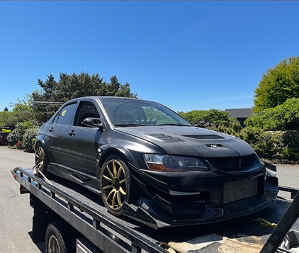 A black car is sitting on top of a tow truck.