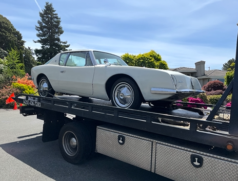 A white car is sitting on top of a tow truck.