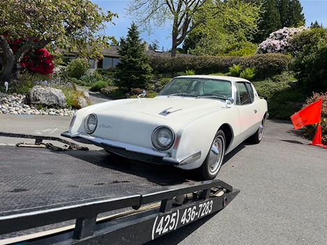 A white car is sitting on top of a tow truck.