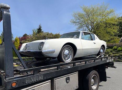 A white car is being towed by a century tow truck.