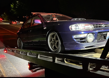 A blue car is sitting on top of a tow truck.