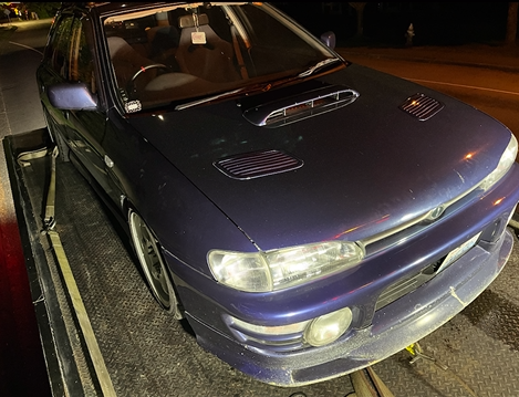 A purple car is sitting on top of a tow truck.