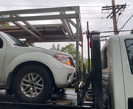 A white truck is sitting on top of a tow truck.