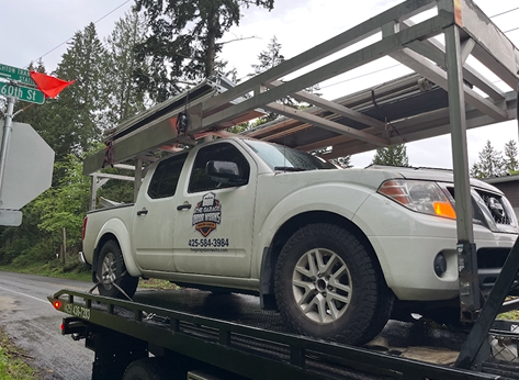 A white truck is sitting on top of a tow truck.