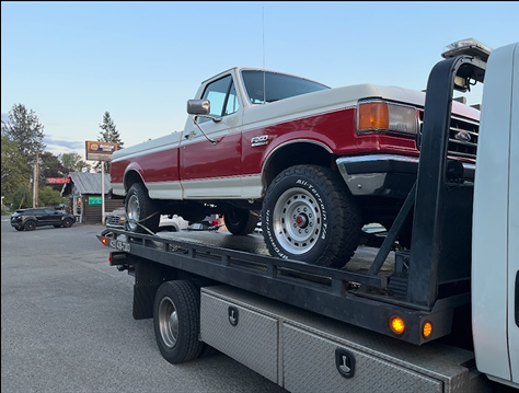 A red and white truck is being towed by a tow truck.