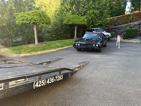 A black car is being towed by a tow truck.
