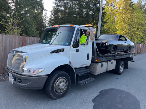 A tow truck is carrying a car on the back of it.