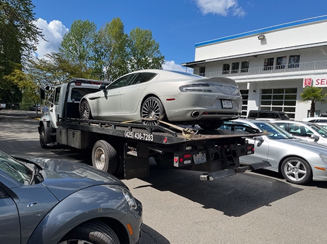 A car is being towed by a tow truck in a parking lot.