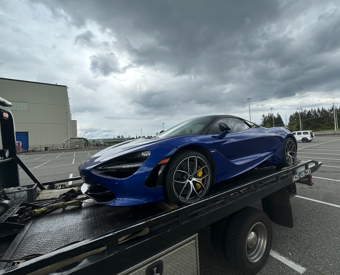 A blue sports car is being towed by a tow truck.