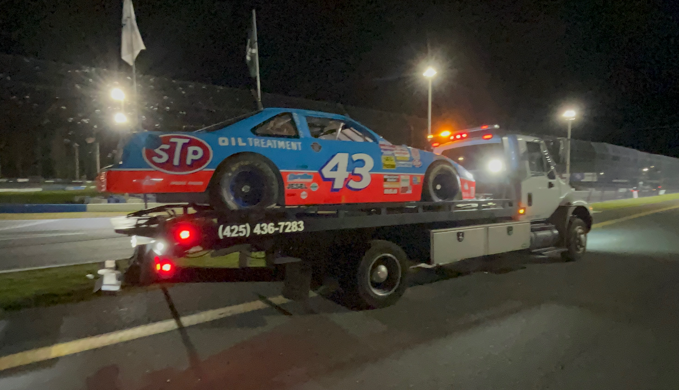 A race car is being towed by a tow truck.