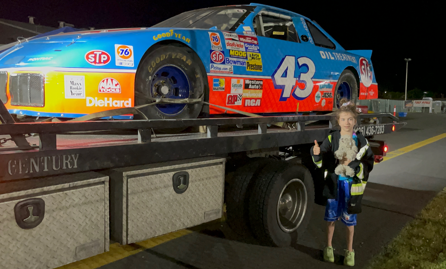 A boy is standing next to a race car with the number 43 on it