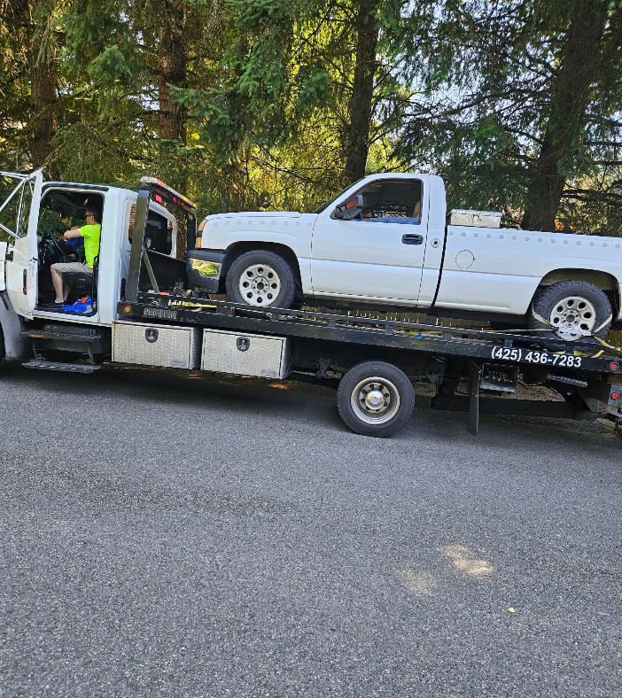 A white truck is being towed by a tow truck.