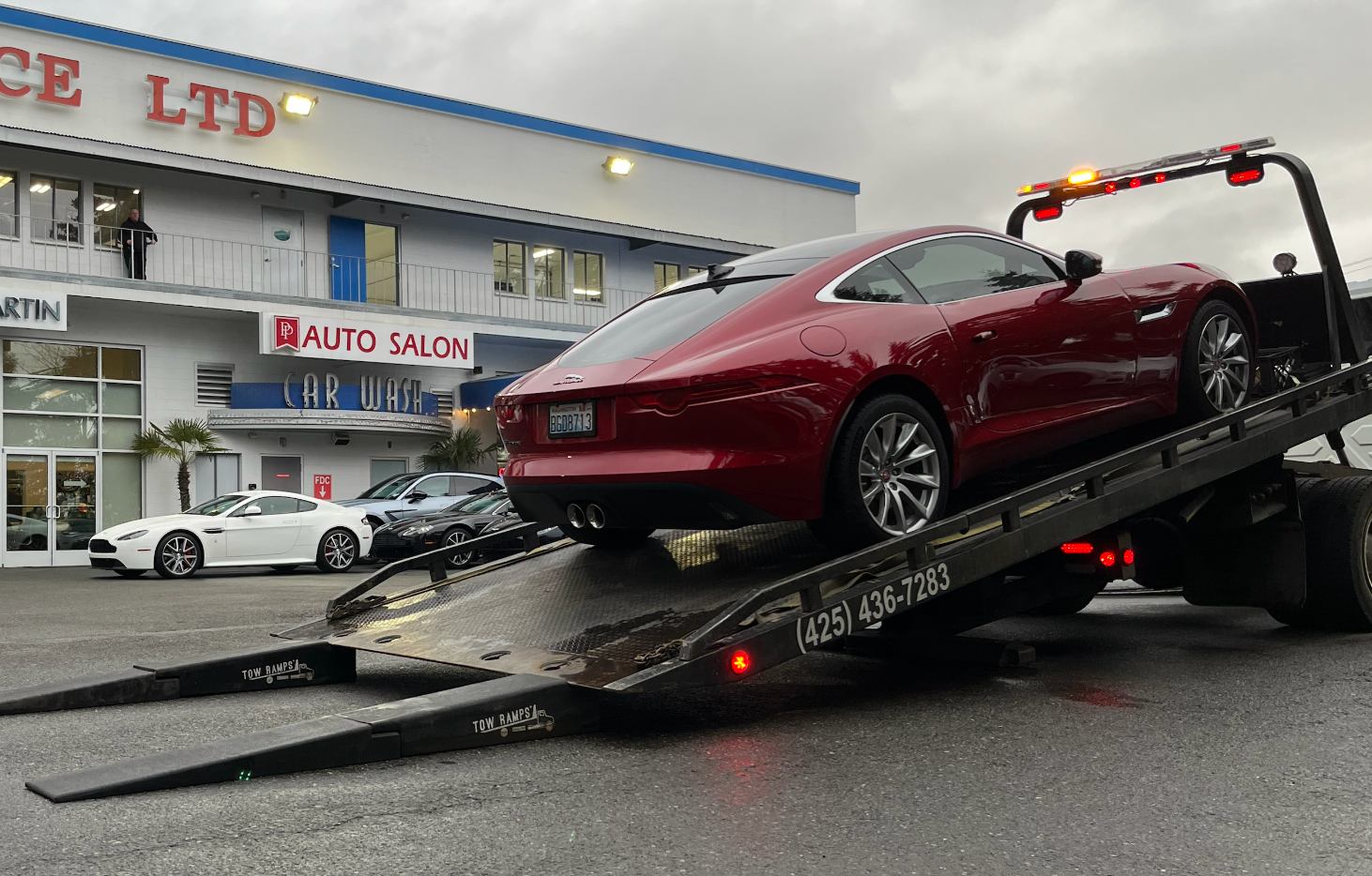 A red sports car is being towed by a tow truck