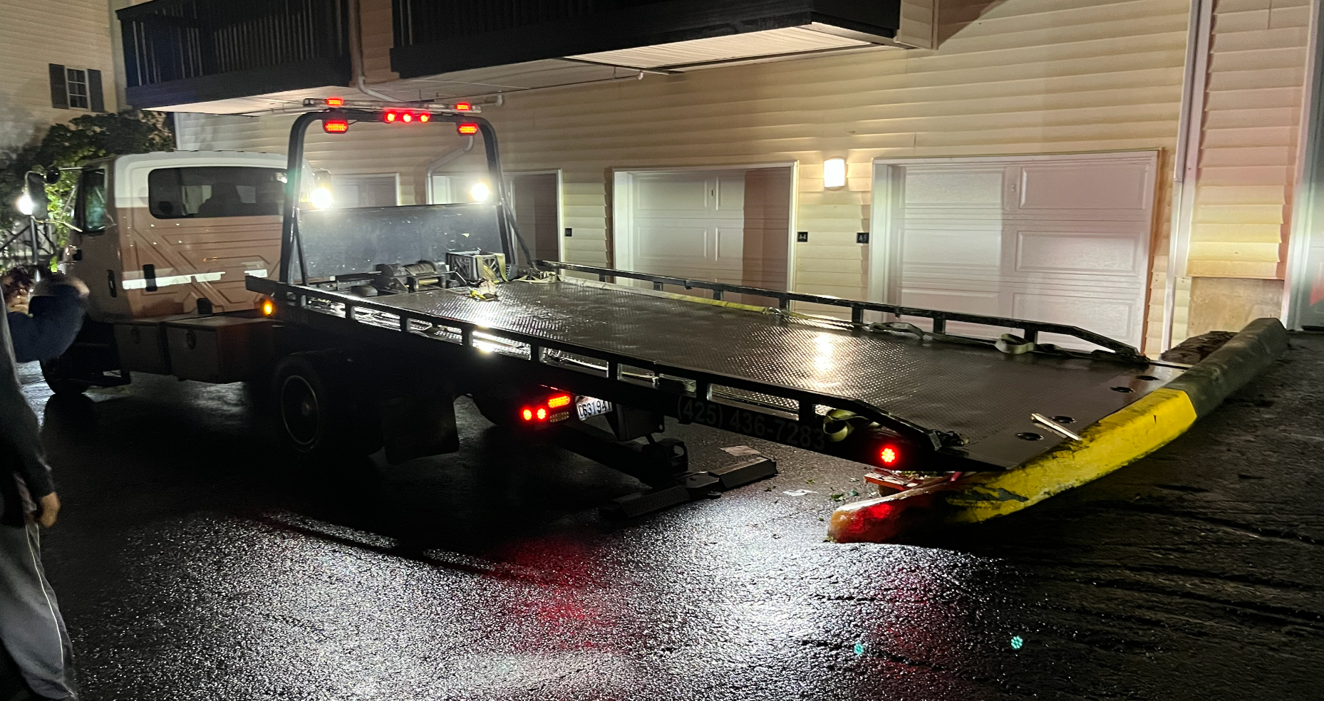 A tow truck is parked in front of a house at night.