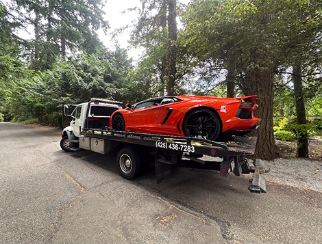 A red lamborghini aventador is being towed by a tow truck.