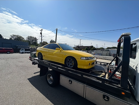 A yellow car is being towed by a tow truck.