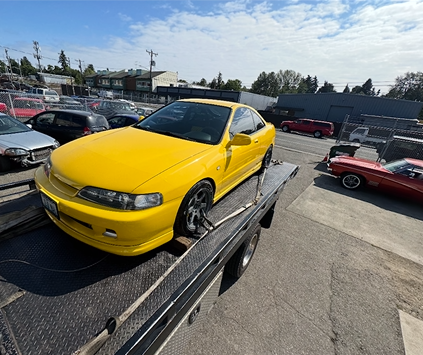 A yellow car is sitting on top of a tow truck.