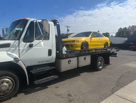 A yellow car is being towed by a tow truck.