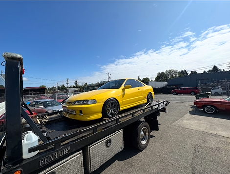 A yellow car is being towed by a century tow truck.