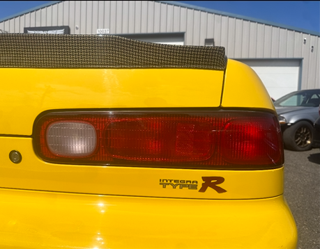 A yellow car with a sticker that says hybrid r