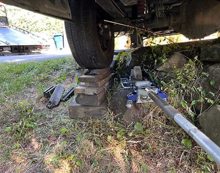 A car is sitting on blocks in the grass next to a tow truck.