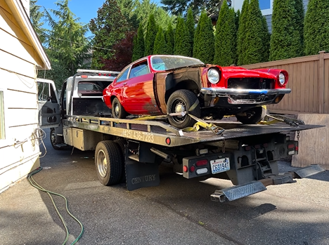 A red car is sitting on top of a tow truck.