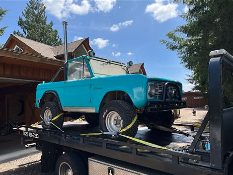 A blue truck is sitting on top of a tow truck.