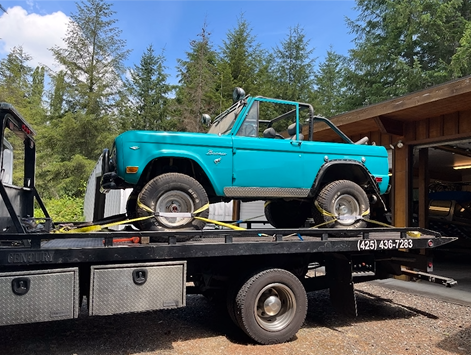 A blue truck is sitting on top of a tow truck.