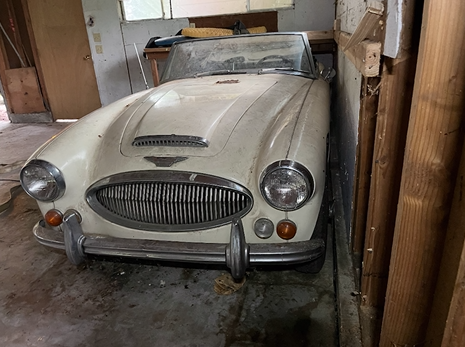 A white sports car is parked in a garage.