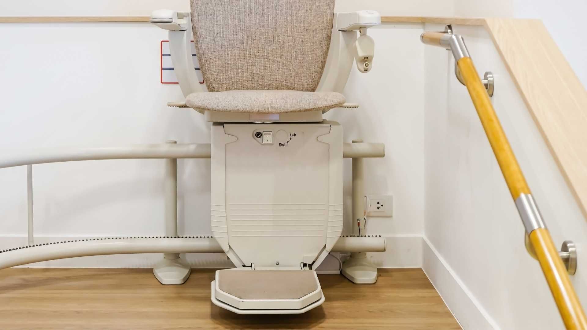 A stair lift is sitting in the corner of a room next to a staircase.