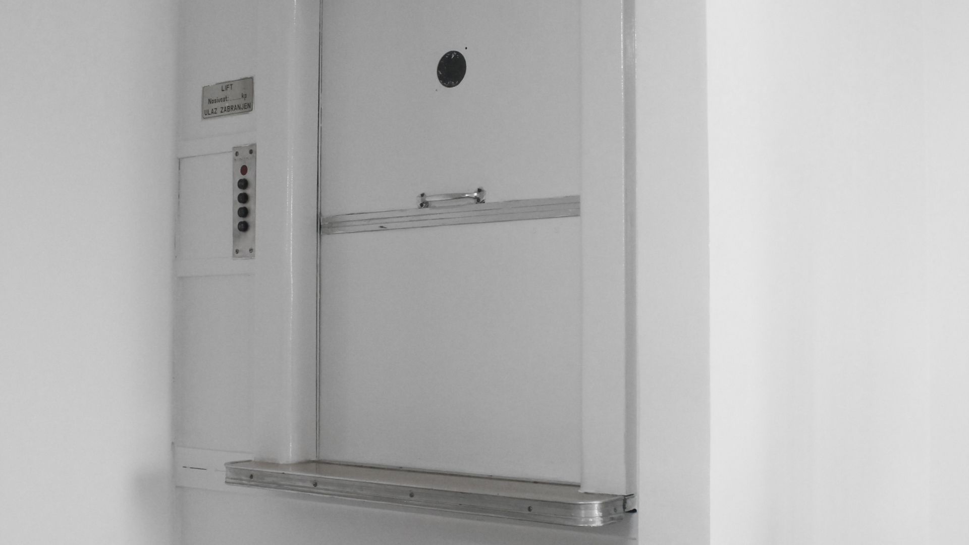 A white door with a hole in it is hanging on a white wall.