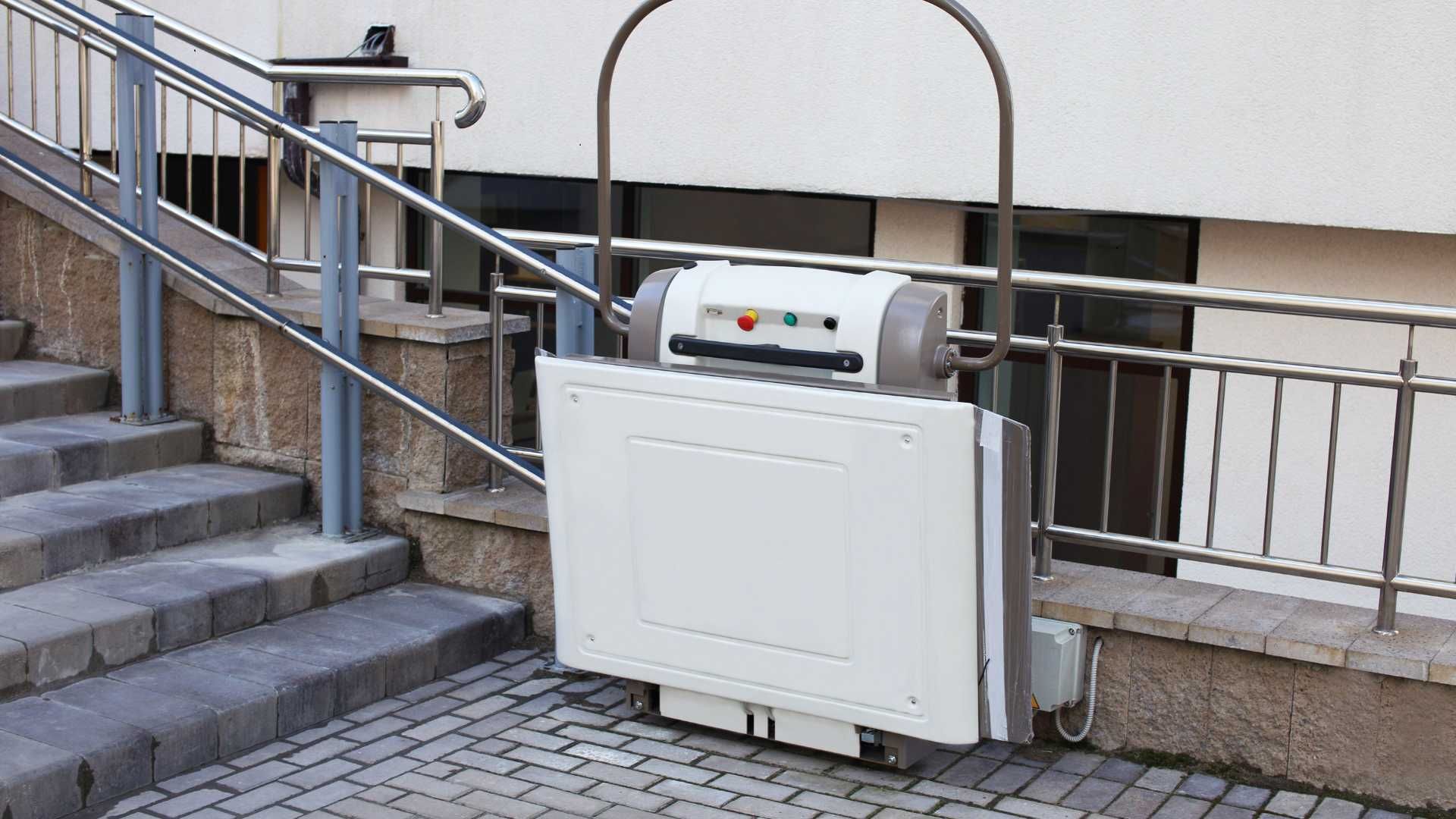 A white stair lift is sitting next to a set of stairs.