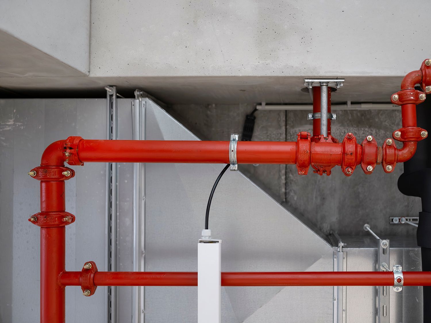 Red fire sprinkler pipes mounted under a concrete ceiling in an industrial space