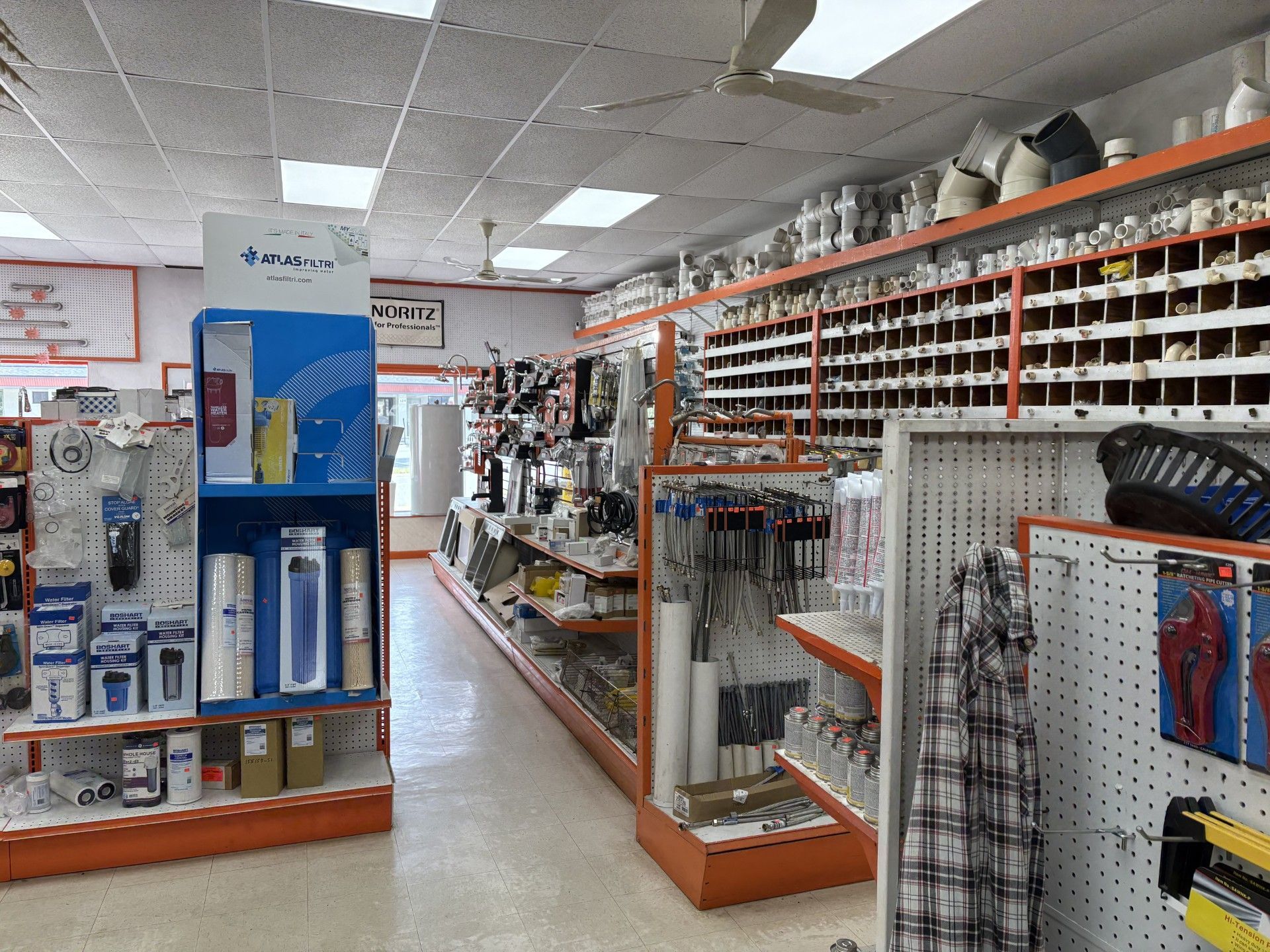 Wide aisle in a warehouse store with tall shelves stocked with boxes and goods on both sides. Wide aisle in a warehouse store with tall shelves stocked with boxes and goods on both sides.
