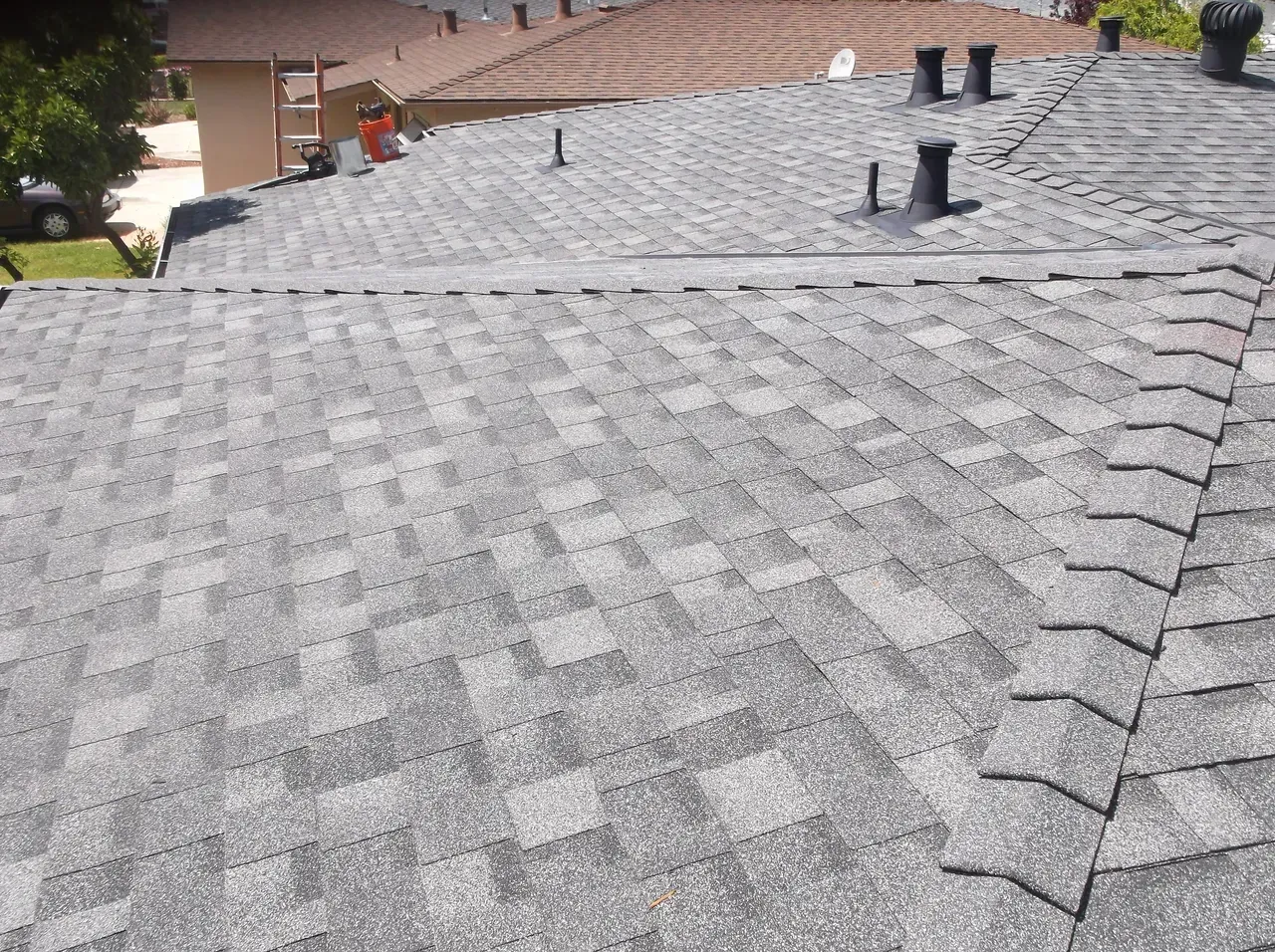 Gray asphalt shingle roof with vents and a gutter, seen from above.