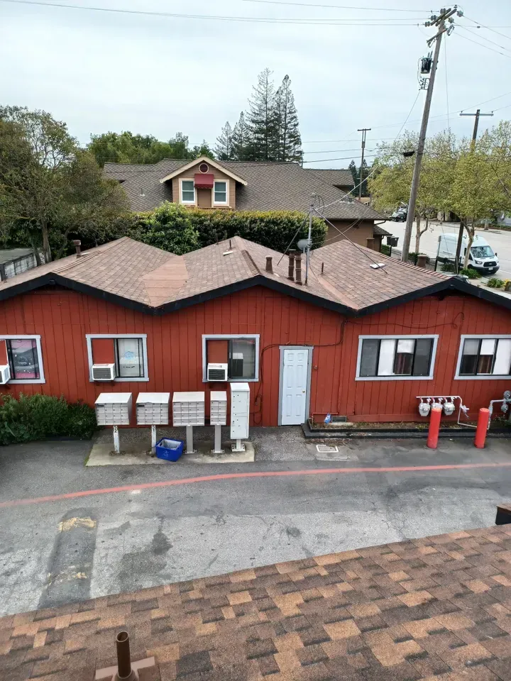 Red building with angled roof; mailboxes in front. A second building is in the background. Cloudy sky.