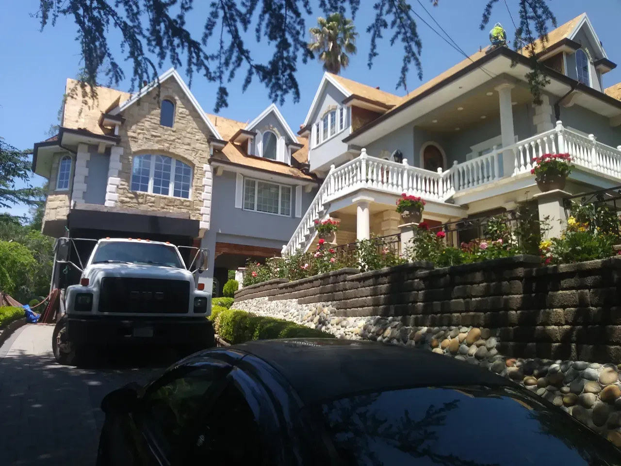 Truck in driveway in front of a large house with a stone facade and multiple levels.