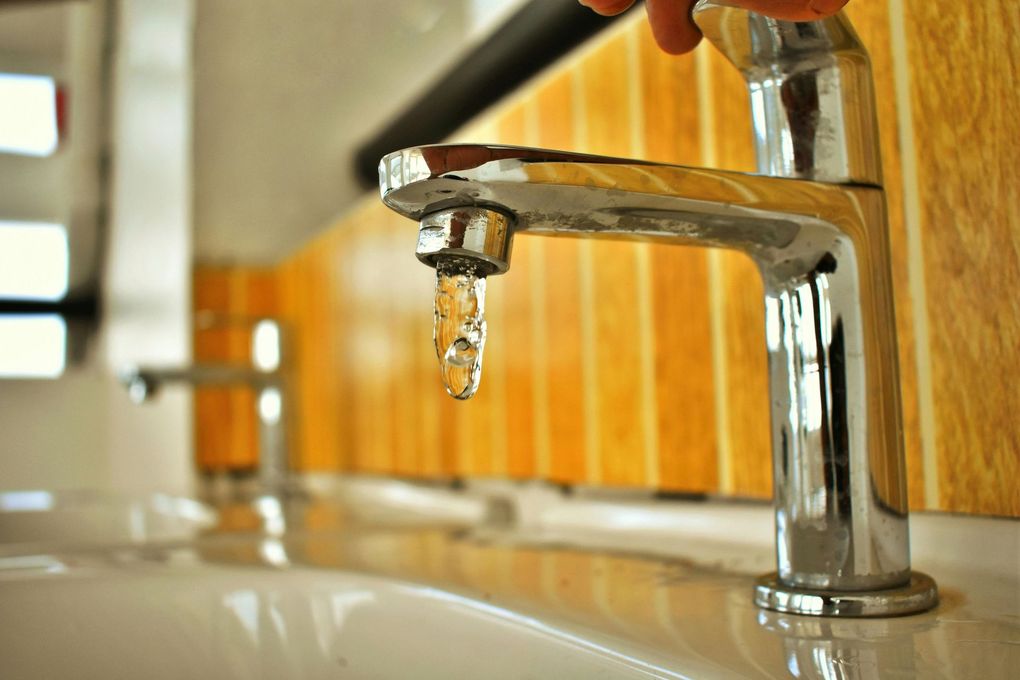 Chrome faucet with water dripping, in bathroom setting.
