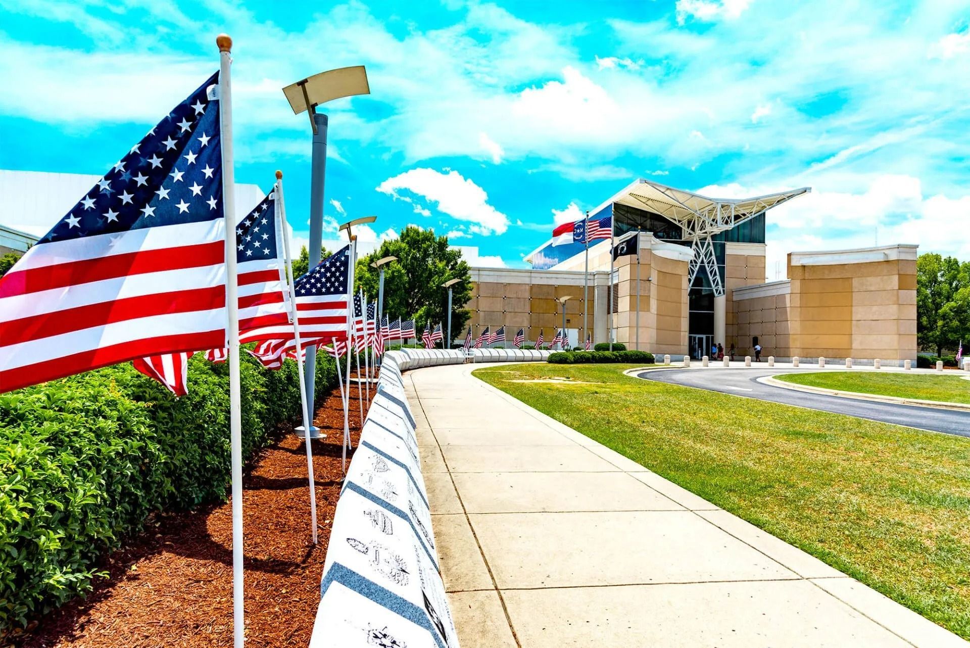 A woman is holding an american flag and a rose at a funeral.